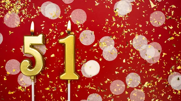 Altın yanan mum numarası 51 numara. Kırmızı arka planda 51 yazısıyla konfeti ve simle birlikte doğum günü tebrik kartı. Yıldönümü, kutlama etkinliği ve doğum günü konsepti.