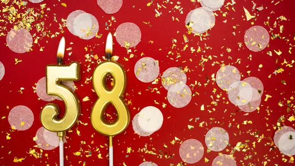 Altın yanan mum numarası 58 'di. Kırmızı arka planda 58 yazılı konfeti ve simli doğum günü tebrik kartı. Yıldönümü, kutlama etkinliği ve doğum günü konsepti.