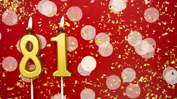 Altın yanan mum numarası seksen bir. Kırmızı arkaplanda konfeti ve simle birlikte 81 yazılı doğum günü tebrik kartı. Yıldönümü, kutlama etkinliği ve doğum günü konsepti.