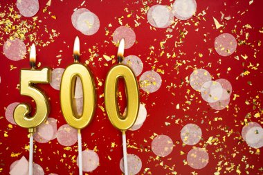 Kırmızı konfeti arka planında yanan altın doğum günü mumları, 500 numara, kopyalama alanı
