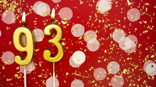 Altın yanan mum numarası doksan üç. Kırmızı arkaplanda 93 yazılı doğum günü tebrik kartı konfeti ve simle. Yıldönümü, kutlama etkinliği ve doğum günü konsepti.