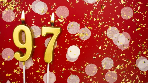 Altın yanan mum numarası doksan yedi. Kırmızı arka planda 97 yazılı doğum günü tebrik kartı konfeti ve simle. Yıldönümü, kutlama etkinliği ve doğum günü konsepti.