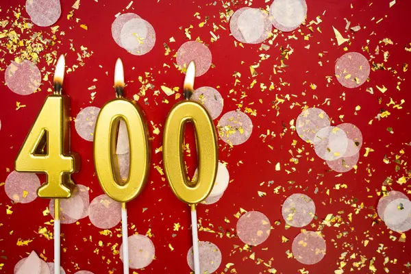 Kırmızı konfeti arka planında yanan altın doğum günü mumları, numara 400. Kopyalama alanı