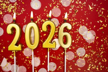 Mutlu yıllar 2026. Tatil geçmişi. 2026 yılının sayıları kırmızı arka planda konfeti ve simle altın mum yakmaktan. Yeni yıl tatili kavramı. Boşluğu kopyala