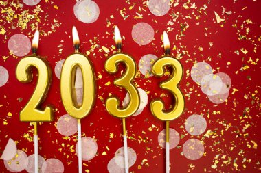 Mutlu yıllar 2033. Tatil geçmişi. 2033 yılının sayıları kırmızı arka planda konfeti ve simle altın mum yakmaktan. Yeni yıl tatili kavramı. Boşluğu kopyala
