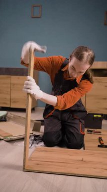 Oturma odasında ahşap raflarla çalışan profesyonel mobilya montajcısı. Genç tamirci montaj işinde. Boşluğu kopyala