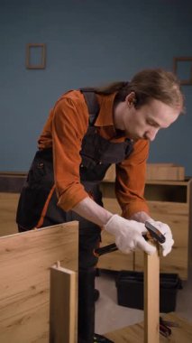 Oturma odasında ahşap raflarla çalışan profesyonel mobilya montajcısı. Genç tamirci montaj işinde. Boşluğu kopyala