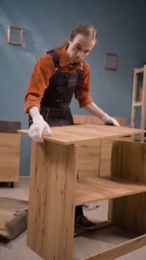 Oturma odasında ahşap raflarla çalışan profesyonel mobilya montajcısı. Genç tamirci montaj işinde. Boşluğu kopyala