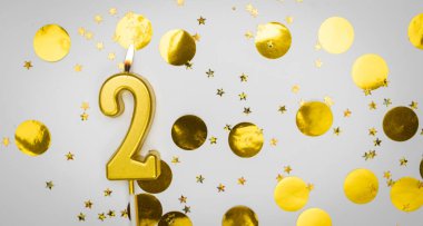 Beyaz arka planda altın konfeti ve simle yanan 2 numaralı doğum günü mumu. İki yaşında. Doğum günün kutlu olsun. Şenlik arka planında kart. Pankart