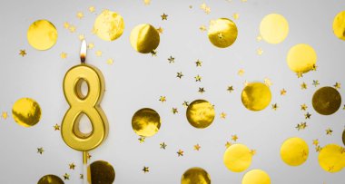 Beyaz arka planda, altın konfeti ve simle birlikte 8 numaralı yanan doğum günü mumu. Sekiz yaşında. Doğum günün kutlu olsun. Geçmiş şenliği kartı. Bayrak