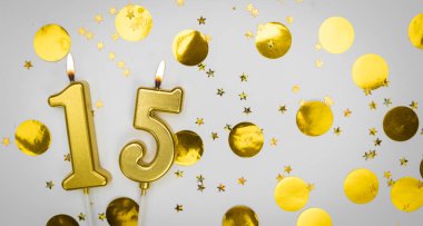 Beyaz arka planda altın konfeti ve sim ile 15 numaralı yanan doğum günü mumu. On beş yaşında. Doğum günün kutlu olsun. Geçmiş şenliği kartı. Bayrak