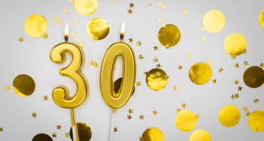 Beyaz arka planda, altın konfeti ve simle 30 numaralı yanan doğum günü mumu. Otuz yaşında. Doğum günün kutlu olsun. Geçmiş şenliği kartı. Bayrak