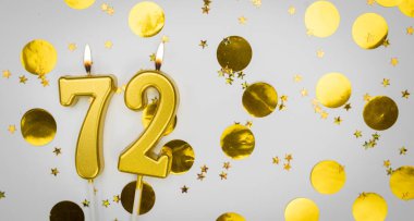 72 numaralı doğum günü mumu beyaz üzerine konfeti arkaplanlı. 72 'nci yaş günü. Doğum günü ve yıldönümü kutlaması kavramı. Boşluğu kopyala