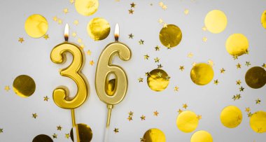 36 numaralı yanan doğum günü mumu beyaz arka planda altın konfeti ve sim ile. Otuz altı yaşında. Doğum günün kutlu olsun. Geçmiş şenliği kartı. Bayrak