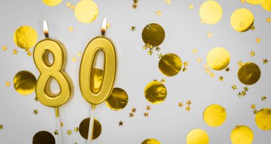 80 numaralı doğum günü mumu beyaz üzerine konfeti arkaplanlı. Seksen yıllık doğum günü. Doğum günü ve yıldönümü kutlaması kavramı. Boşluğu kopyala
