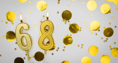 68 numaralı doğum günü mumu beyaz üzerine konfeti arkaplanlı. Altmış sekiz yıllık doğum günü. Doğum günü ve yıldönümü kutlaması kavramı. Boşluğu kopyala