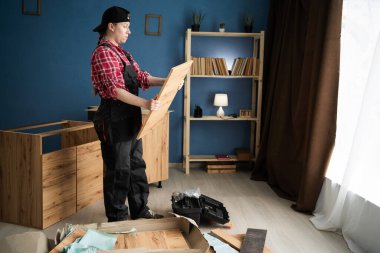 Oturma odasında toplantı sırasında kadın mobilya montajcısı dolabın kapısını tutuyor. Boşluğu kopyala