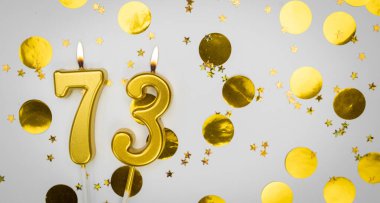 73 numaralı doğum günü mumu beyaz üzerine konfeti arkaplanlı. 73 'üncü yaş günü. Doğum günü ve yıldönümü kutlaması kavramı. Boşluğu kopyala