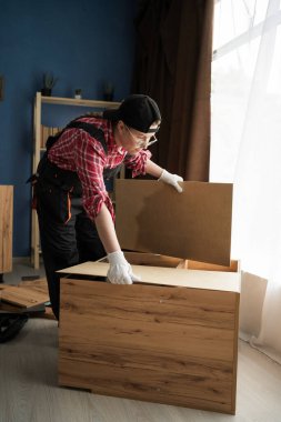 Mobilya montajı. Derleyici taşınmak için rafı alıyor. Boşluğu kopyala