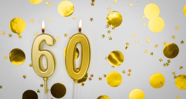 60 numaralı yanan doğum günü mumu beyaz arka planda altın konfeti ve sim ile. Altmış yaşında. Doğum günün kutlu olsun. Geçmiş şenliği kartı. Bayrak