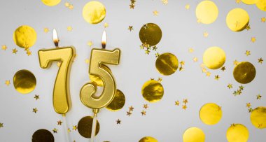 75 numaralı doğum günü mumu beyaz üzerine konfeti arkaplanlı. Yetmiş beş yıllık doğum günü. Doğum günü ve yıldönümü kutlaması kavramı. Boşluğu kopyala