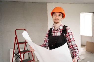 Proje planı olan bir işçi. İnşaat işçisi yeni bir binayı ziyaret ederken çalışıyor. İnşaat alanı kavramı