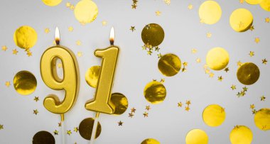 91 numaralı doğum günü mumu beyaz üzerine konfeti arkaplanlı. Doksan birinci yaş günü. Doğum günü ve yıldönümü kutlaması kavramı. Boşluğu kopyala.
