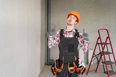 Miğferli işçi ya da müteahhit boş alanda parmaklarını gösteriyor. meslek, inşaat ve inşaat kavramı.