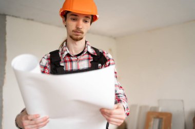 Proje planı olan bir işçi. İnşaat işçisi yeni bir binayı ziyaret ederken çalışıyor. Boşluğu kopyala