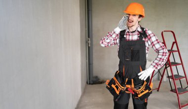 İnşaat alanındaki müteahhit gri duvarın önünde sırları fısıldayarak ya da bağırarak dedikodu yapıyor. Pankart. Boşluğu kopyala