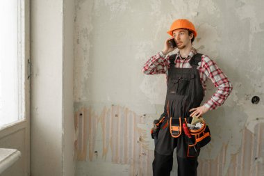 Telefon görüşmesi ve inşaat alanı konsepti. İnşaatçı cep telefonu konuşmalarıyla bina projesinden bahsediyor. Boşluğu kopyala