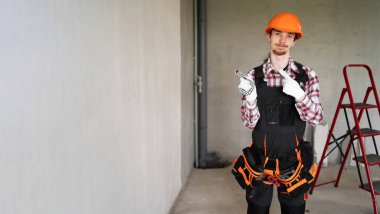 İnşaat işçisi kasklı adam beton duvara karşı reklam alanını işaret ediyor. Ev yapımı ve yenileme konsepti. Boşluğu kopyala