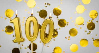 Beyaz üzerine konfeti arkaplanlı 100 numaralı doğum günü mumu. Yüz yıllık doğum günü. Doğum günü ve yıldönümü kutlaması kavramı. Boşluğu kopyala.