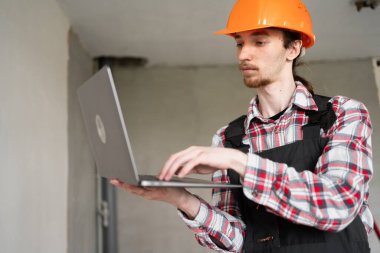 İnşaat ve ev yenileme konsepti. İnşaat planı ve müteahhit. Bilgisayarı kullanarak yenileme projesini oluşturan kişi. Boşluğu kopyala