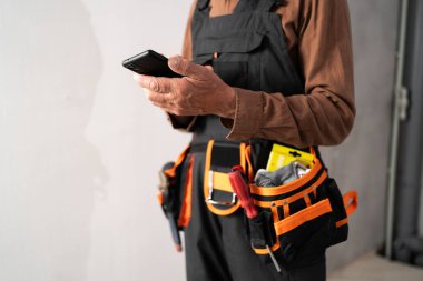 İnşaat alanında telefonlu bir erkek mesaj yolluyor. Bina geliştirme. İnşaat endüstrisi için bilgilendirme ve mobil uygulama. yakın plan