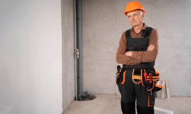 Emniyet kaskı takmış, kollarını çapraz yapmış, olgun bir erkek müteahhit. meslek, inşaat ve inşaat kavramı