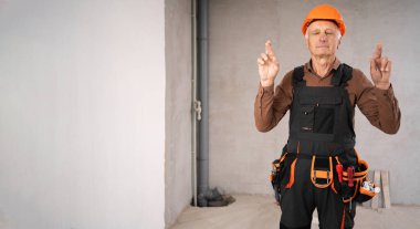 Güvenlik kaskı takmış yaşlı erkek müteahhit parmaklarını çapraz yapıp arzulanan dilekler diliyor. meslek, inşaat ve inşaat kavramı