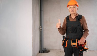 Miğferli yaşlı erkek müteahhit inşaat alanında baş parmak gösteriyor. meslek, inşaat ve inşaat kavramı