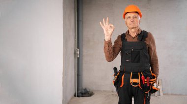 Güvenlik kaskı takmış yaşlı erkek müteahhit iyi bir hareket gösteriyor. meslek, inşaat ve inşaat kavramı