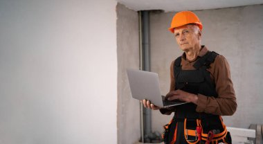 Planlama ve koordinasyon sürecinde inşaat alanında dizüstü bilgisayar kullanan inşaat işçisi. Dijital araçlar, inşaat yönetimi ve modern yapı teknolojisi kavramı.