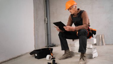 İnşaat alanında çalışan kasklı, eski erkek müteahhit. iş, inşaat ve evrak işleri kavramı.