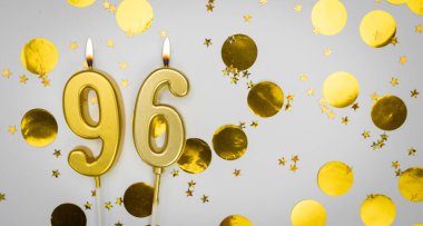 96 numaralı doğum günü mumu beyaz üzerine konfeti arkaplanlı. Doksan altı yıllık doğum günü. Doğum günü ve yıldönümü kutlaması kavramı. Boşluğu kopyala.