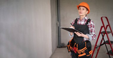 Arka planda boş duvarları olan, panosu olan kadın işçi ya da müteahhit. İnşaat, onarım ve meslek kavramı. Pankart. Boşluğu kopyala