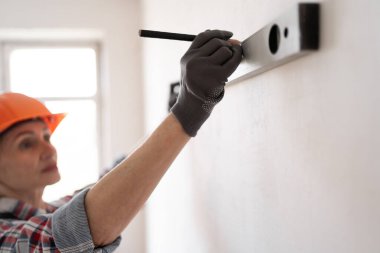 Ev geliştirme ve tamir konsepti. İnşaat, müteahhit ve müteahhit. Kask takan tamirci ruh seviyesini koruyor. Boşluğu kopyala