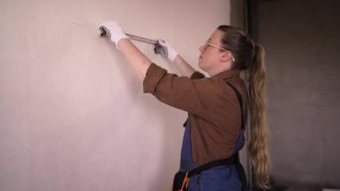 Gözlüklü, cetvelli, evinde duvar ölçen bir kadın. Onarım, inşaat ve inşaat konsepti. Boşluğu kopyala