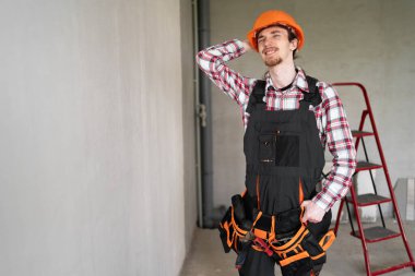 Güvenlik kaskı takan genç müteahhit soru sormayı ciddi ciddi düşünüyor. Boşluğu kopyala