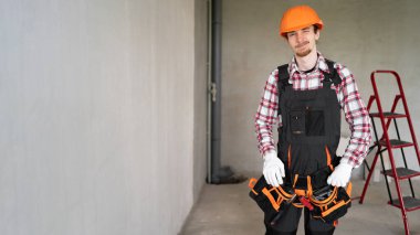 İnşaat işçisi ya da inşaat işçisi. İnşaat alanında kapalı bir yerde dururken kameraya alet kemeriyle göz kırpıyor. Yenileme çalışmaları sırasında flört, mizah ve güven kavramı.