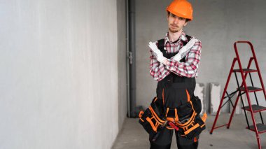 Genç inşaat işçisi ya da inşaatçı mavi tulumlu reddedilme ifadesini kızgın yüzüyle gösteriyor. Boşluğu kopyala