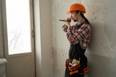 Tadilattan önce eski apartman dairesinde inşaat işçisi olarak duruyor, sesli mesaj gönderiyor ya da yapay zeka asistanıyla konuşuyor. Teknoloji ve meslek kavramı.