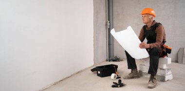 İnşaat alanında başlık takan son sınıf öğrencisi. İnşaat işçisi ev okuma planı yeni binada çalışıyor. Pankart. Boşluğu kopyala